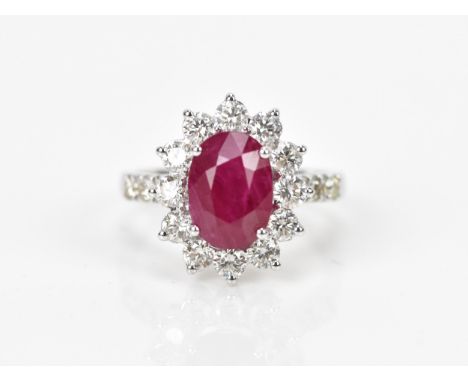 An 18ct white gold, diamond and ruby dress ring, set with central oval mixed cut ruby in four claw setting, with a halo of tw