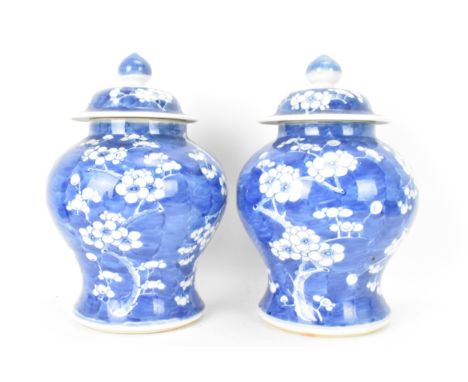A pair of Chinese prunus pattern blue and white vases, late Qing Dynasty, both of baluster form with domed cover and knopped 