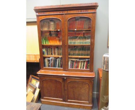 A mid-Victorian mahogany library bookcase with arched glazed doors and panel doors, below on a plinth base, 230 x 134 x 48cm.