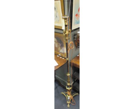 A black and gold coloured standard lamp with figure decoration on lion paw feet, 147cm.  