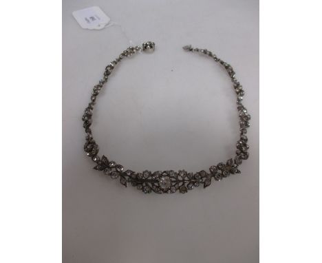 A late 19th/early 20th century paste set necklace, the central panel set as two sprigs facing each other with smaller leaf sh