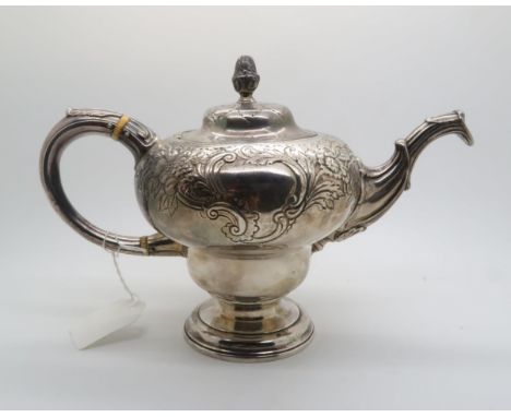 A Scottish white metal 18th century style teapot of inverted pear shape upon a footed circular base, the upper body chased wi