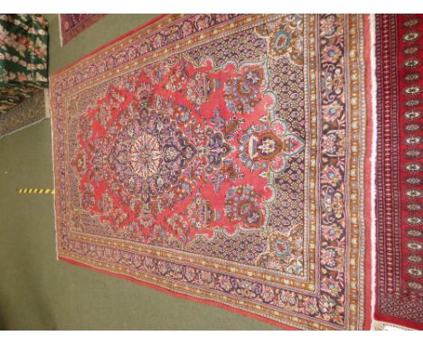 Persian carpet, rust ground within a puce border &  all over floral decoration