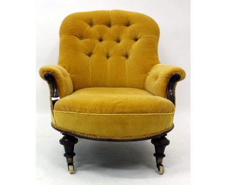 A VICTORIAN MAHOGANY FRAMED YELLOW UPHOLSTERED BUTTON BACK TUB CHAIR with turned legs and ceramic casters, 71cm wide