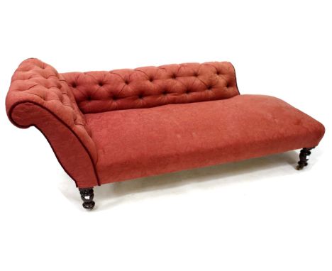 A RE-UPHOLSTERED BUTTON BACK CHAISE LONGUE on bun feet with brass castors