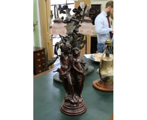 A BRONZED RESIN FIGURAL TABLE LAMP the glass shades depicting flowers 74cm high