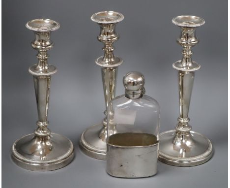 Assorted plated wares to include three candlesticks and a spirit flask