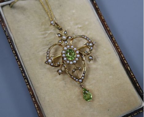 An Edwardian 9ct, peridot and seed pearl set drop pendant on a yellow metal chain, pendant 40mm.