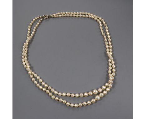 A twin strand graduated cultured pearl necklace with yellow metal and four stone diamond set clasp, 52cm
