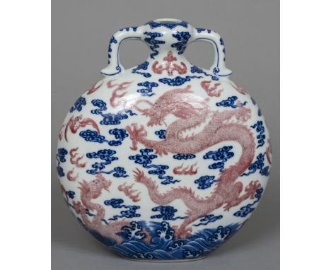 A Chinese porcelain twin handled moon flask
Decorated with iron red bats and dragons amongst stylised clouds and waves, blue 