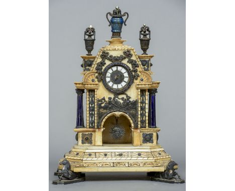 A 19th century Continental white metal gem set and enamelled ivory timepiece
The architectural case with urn finials, scrolli