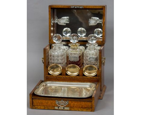 A Victorian oak three bottle tantalus/games compendium
The silver plate mounted hinged top with mirrored interior fitted with