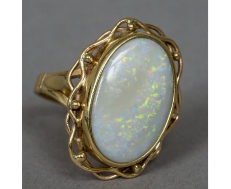 A 9 ct gold opal set ring
The large white cabochon opal set in scrolling framework.  2.5 cm high. CONDITION REPORTS: Generall