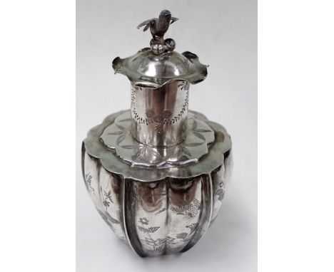 A Chinese silver coloured metal lidded tea canister of lobed form with song bird finial to lid. The exterior chased with exot
