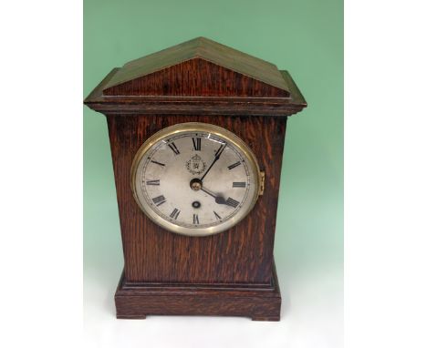 A rare RAF Officer’s desk clock. Plain arch top oak case with silvered dial and Roman numerals with wreathed RAF motif. Singl