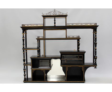 An Aesthetic Movement ebonized wall shelf with pierced brass galleries. Bevelled glass cabinets, gilded decorations. 155cm wi