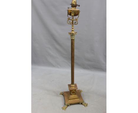 A late Victorian brass Corinthian column drawing room oil lamp. Plinth base rests on four paw feet. Electrified. 180cm high.