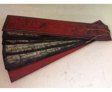 A red lacquered framed prayer or manuscript book containing seven metal leaves with caligraphy and figures, possibly of Burme