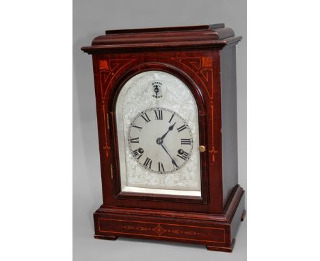 An Edwardian mahogany and inlaid bracket clock. Silvered and engraved arch dial. With Roman numerals and strike/silent dial. 