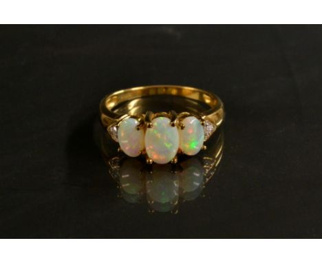 An opal and diamond ring, three graduating oval opal doublets flashing , red, violet, orange green and blue colour play, flan