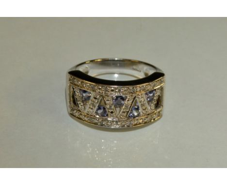 A tanzanite and diamond panel ring, V lattice crest inset with five round tanzanite's and twenty four diamond accents, 9ct go