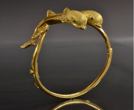 An unusual hinge bangle as two leaping fish, each inset with emerald eyes, diamond mouths, fins and tails, total estimated di