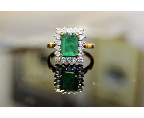 An emerald and diamond cluster ring, central rectangular emerald measuring approx 9mm x 7mm x 4 mm, estimated carat weigh app