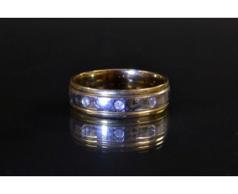 A two tone yellow and white gold diamond band ring, central band of white gold inset with three individually mounted round cu