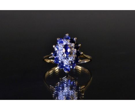 A sapphire and diamond navette cluster ring, triple layer navette crown encrusted with a central blue sapphire, surrounded by