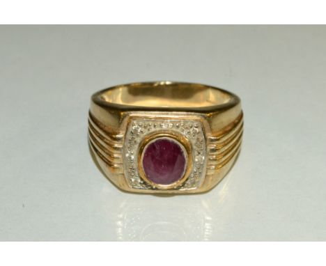 A gentleman's ruby and diamond signet ring, central oval collet set  red ruby, surrounded by a textured platform inset with e