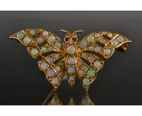 A 9ct gold opal and ruby butterfly brooch, shaped arching body encrusted with forty opals, flashing green, violet, red, orang