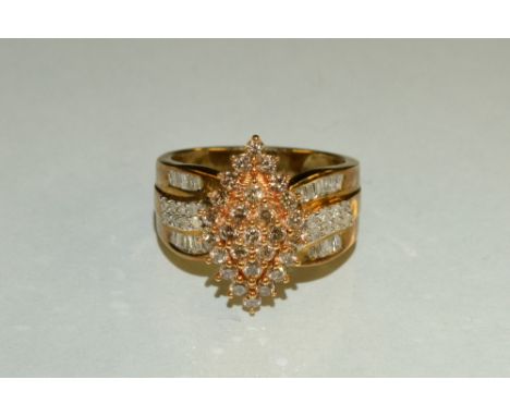 A diamond cluster ring, navette top inset with twenty seven round cognac diamonds, above tapering shoulders inset with twenty