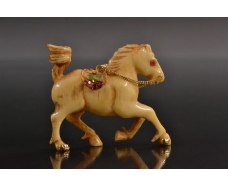 A 19th century Indian carved bone and gem set pendant, as a cantering horse, ruby eyes, ruby, emerald and sapphire set yellow