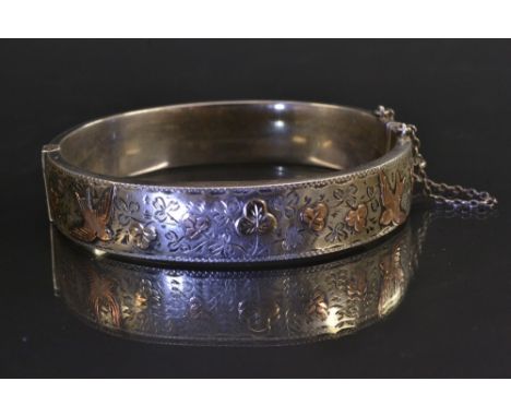 A Victorian silver Aesthetic movement hinge bangle, engraved and inlaid with a gold and copper swooping swallow and floral cr