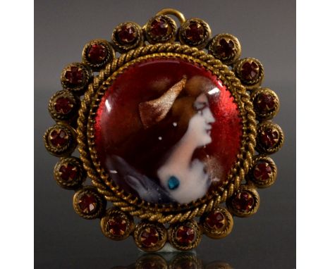 An Art Nouveau enamelled portrait brooch, circular vibrant red portrait maiden facing right, wearing a head scarf, necklace a