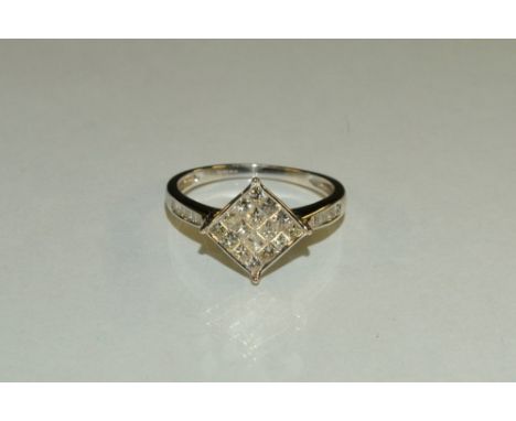 A diamond cluster ring, central navette panel of sixteen square cut diamonds, between diamond set channel shoulders, total di