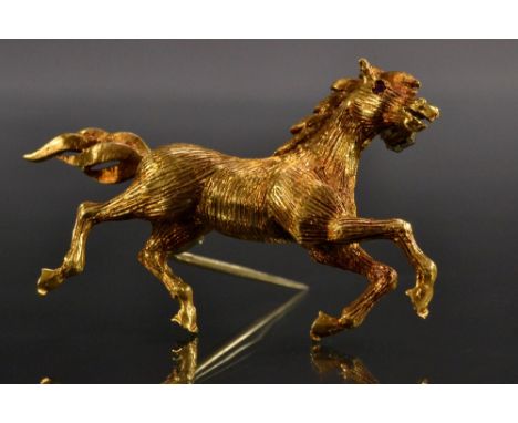 A Vintage 1960s 18ct gold brooch naturalistically modelled as a running horse, inset with a single pale pink ruby eye, import