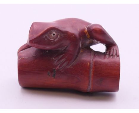 A wood netsuke of a frog perched on a rod of bamboo. 4 cm long.