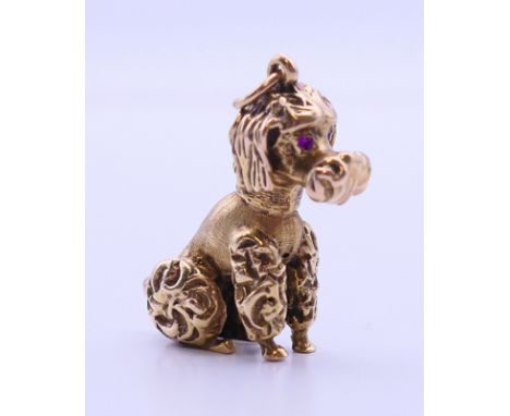 A 9 ct gold poodle dog charm pendant with ruby set eyes.  3 cm high. 11.6 grammes total weight.