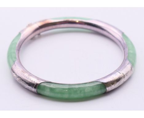 A jade and silver bangle.  5.75 cm internal diameter, 7 cm external diameter, approximately 0.7 cm wide.