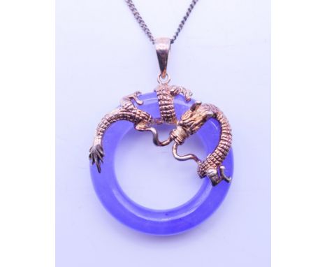 A Chinese lavender jade circular pendant with silver dragon mount on a silver chain. Pendant 2.5 cm diameter, chain 40 cm lon