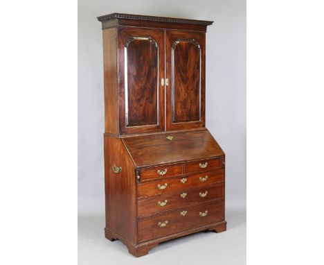 An early George III Cuban mahogany bureau bookcase, the dentil moulded pediment above a pair of arched panel doors, the sides