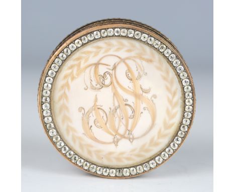 A late 18th century gold mounted circular snuff box, the glazed lid with scrolling hairwork initials within a paste set surro