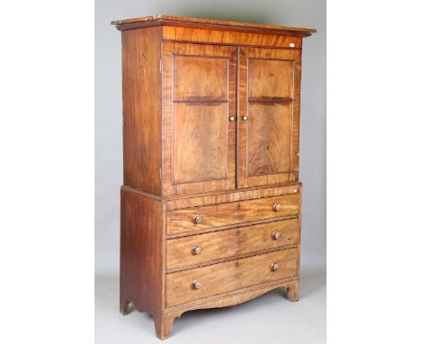 An early 19th century mahogany linen press, the moulded pediment above a pair of panelled doors and three long drawers, on br