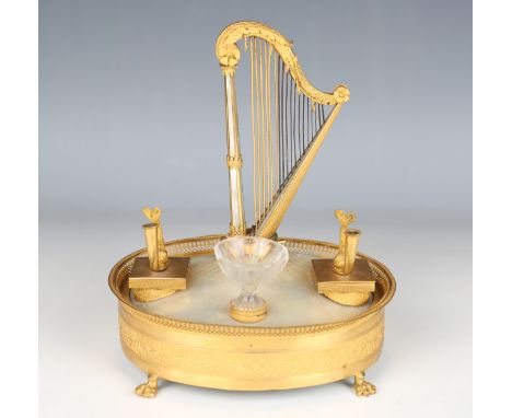 A late 19th century French Classical Revival gilt metal and mother-of-pearl oval musical desk stand, the central harp flanked