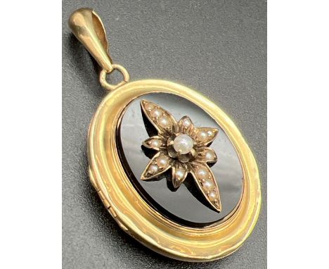 An antique Victorian 24ct gold locket set with onyx panels back &amp; front and ornate seed pearl centre design to front. Wit
