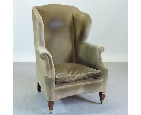 A green upholstered button back wing armchair, on square tapered legs
