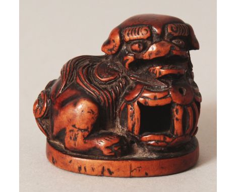 A JAPANESE EDO/MEIJI PERIOD CARVED WOOD NETSUKE OF A SHI-SHI LION DOG, its head resting on a pierced brocaded ball, 1.75in lo