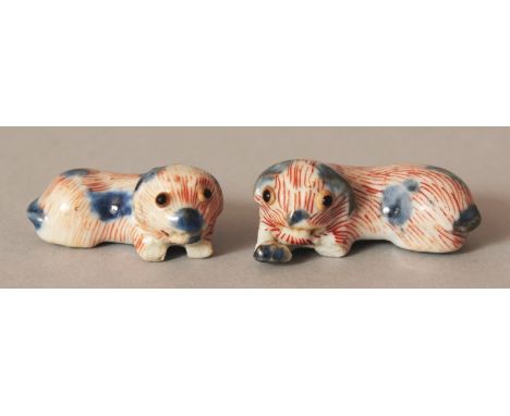 AN UNUSUAL PAIR OF JAPANESE IMARI PORCELAIN NETSUKE OF RECUMBENT SHI-SHI LION DOGS, 1.75in & 1.5in long.