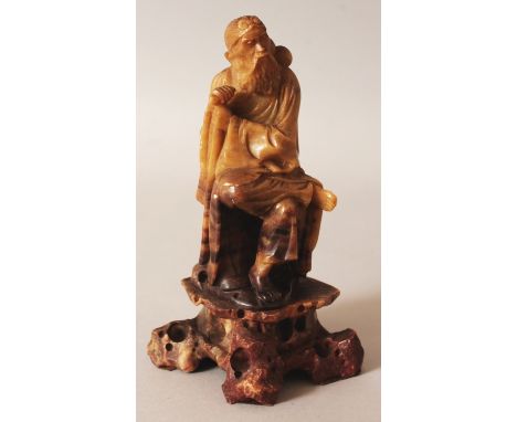 AN EARLY 20TH CENTURY CHINESE CARVED SOAPSTONE FIGURE OF LI TIEGUAI, seated on a rocky plinth, the sage with his crutch and g